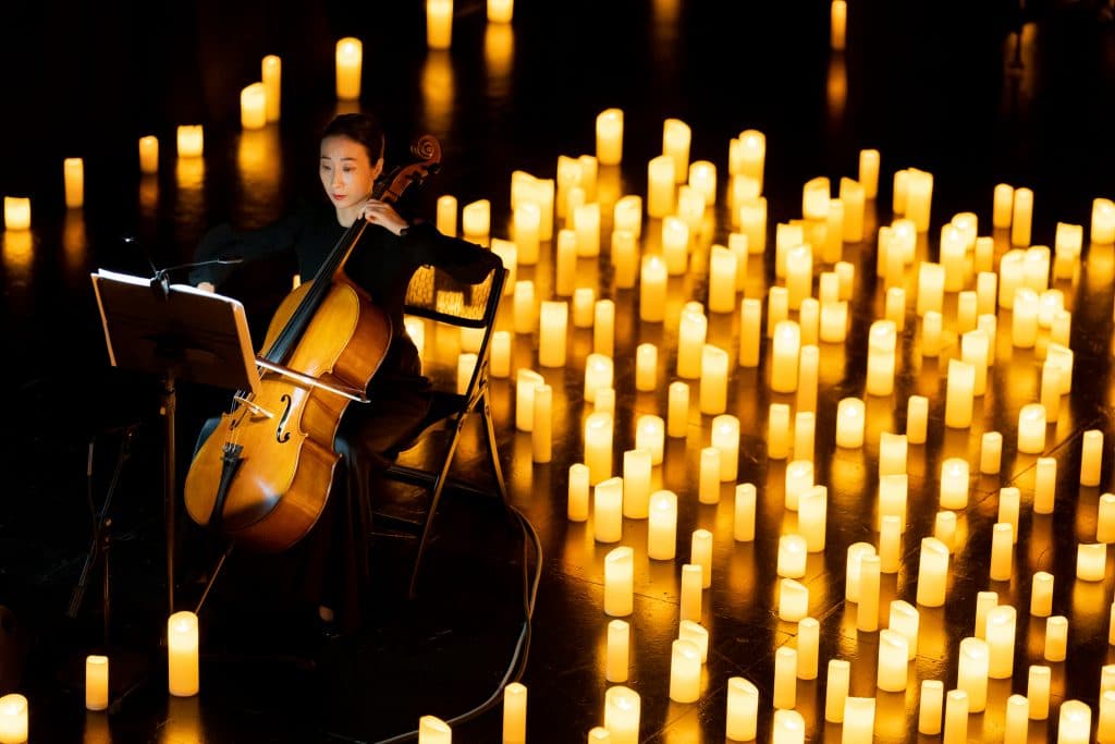 musician playing cello surrounded by candles