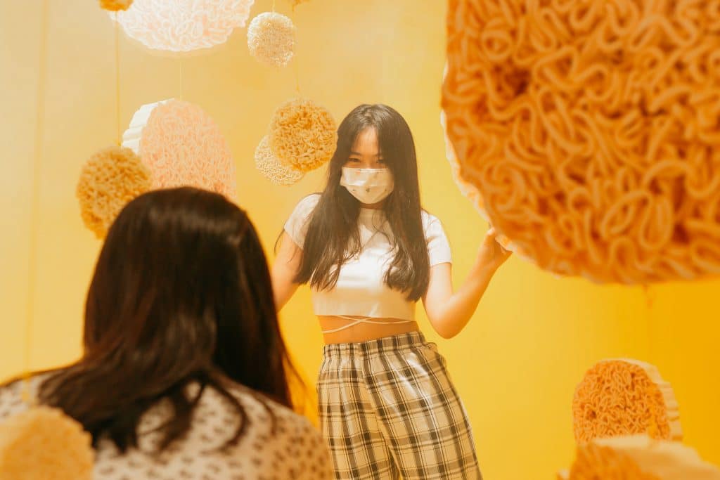 young woman posing in front of instant noodle installation