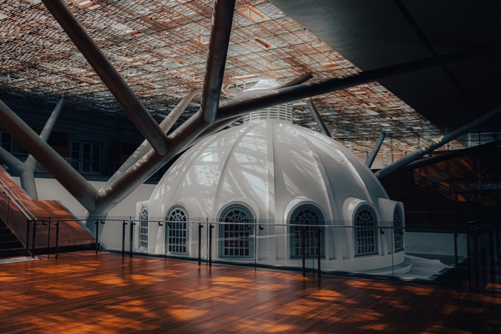 interior of national gallery of singapore showing domed roof inside of modern styled interior and wood flooring