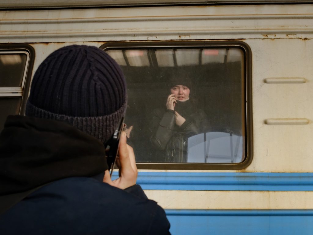 silhouette of person taking photo of person through train window who is speaking on the phone