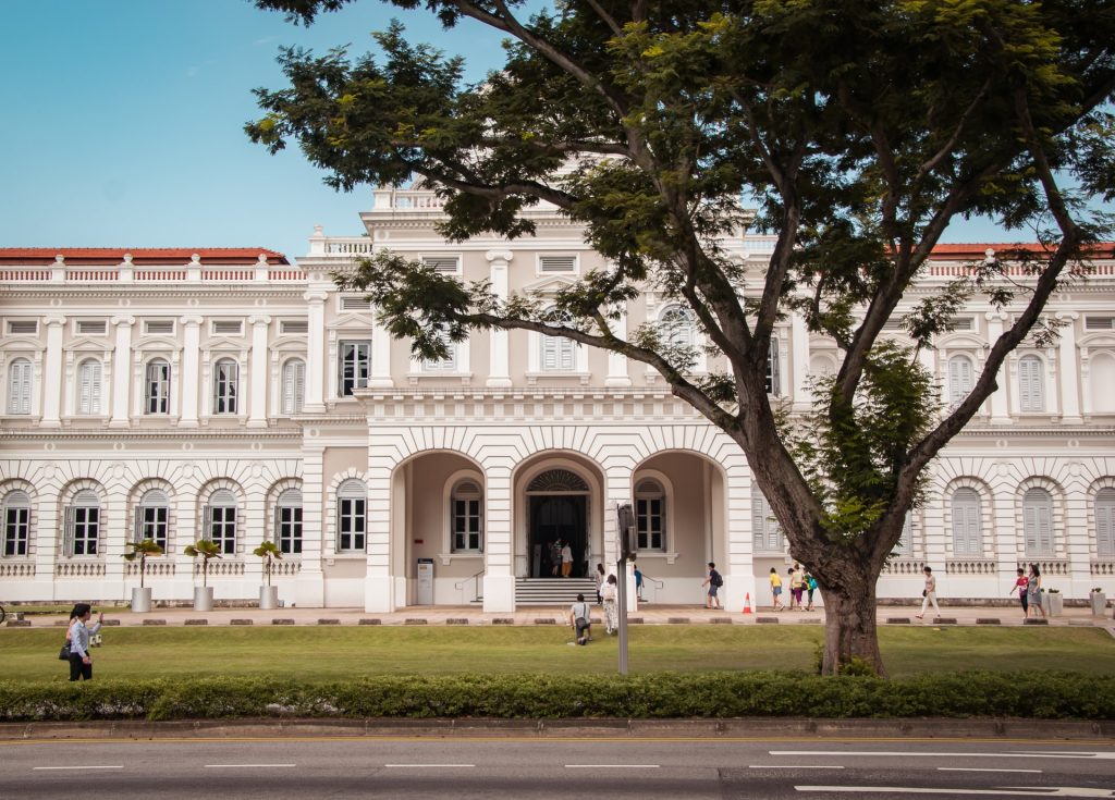 white facade of national museum of singapore with a tree in front