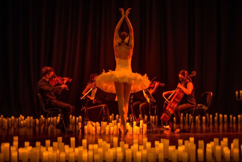 ballerina in front of string quartet and surrounded by candles