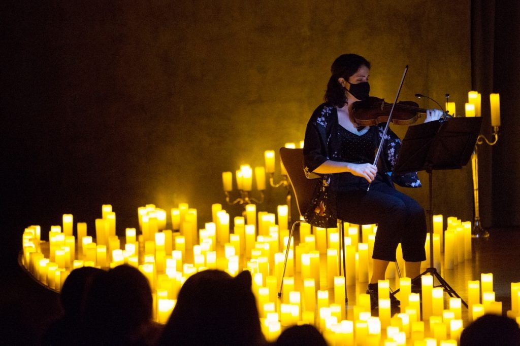 violinist performing surrounded by candles