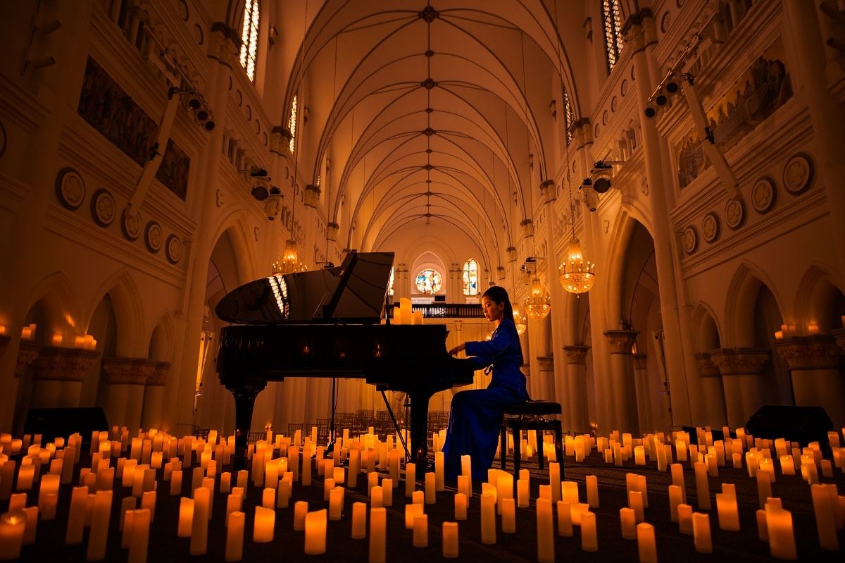 pianist playing piano surrounded by hundreds of candles in iconic building