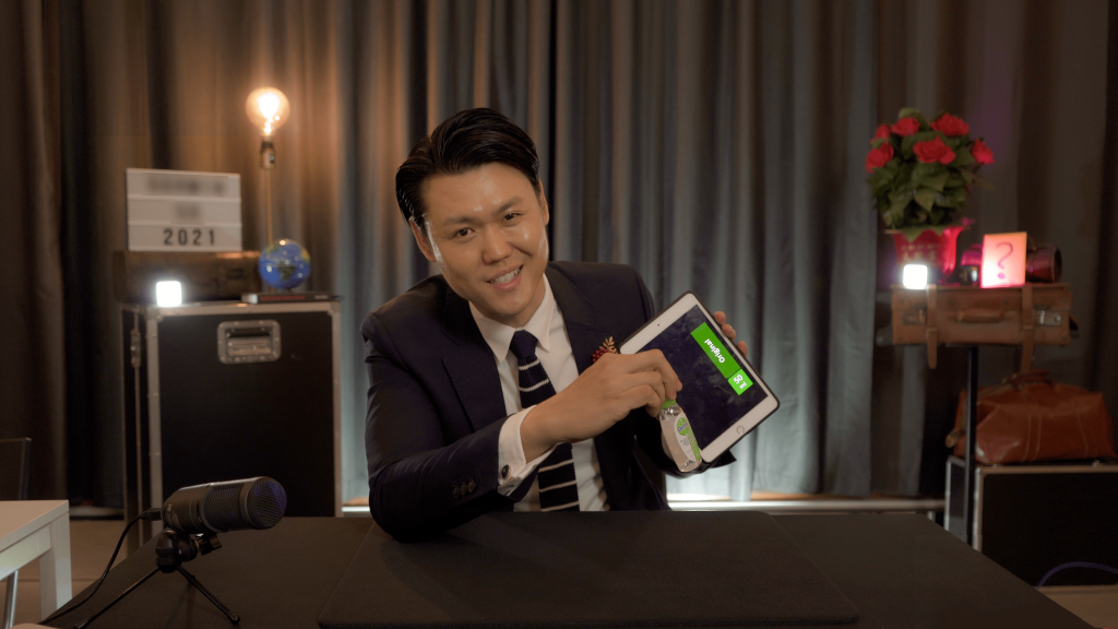 promo shot of alexander yuen magician holding ipad while seated at table