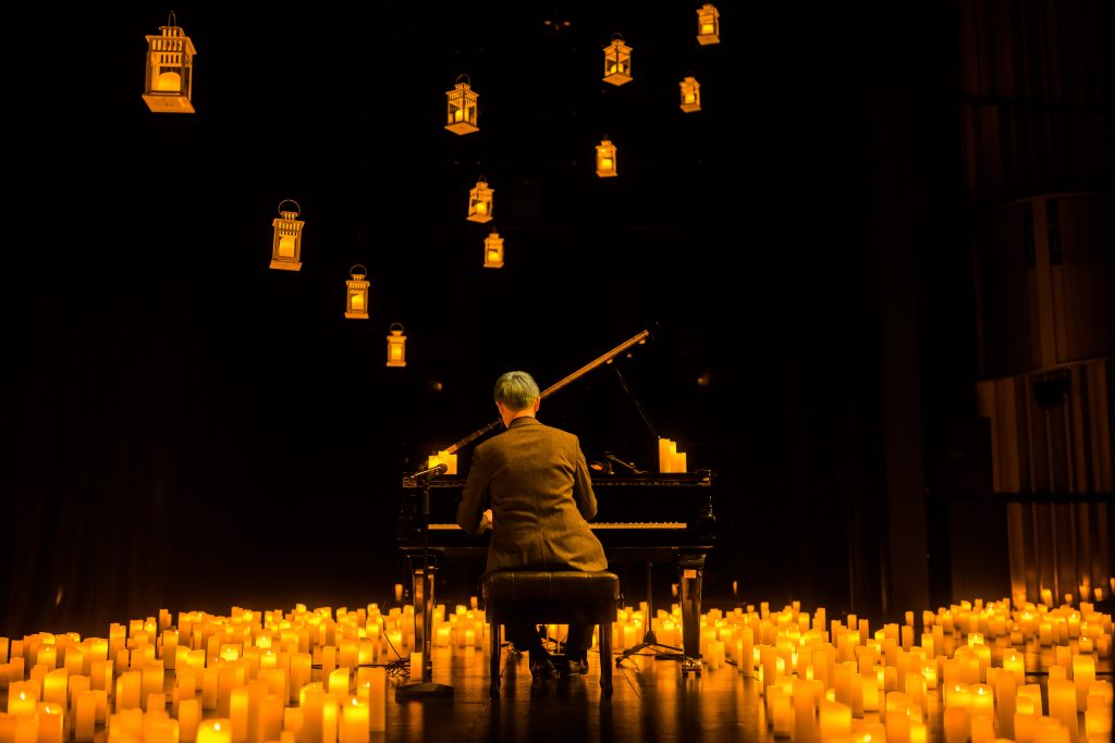 image of pianist performing from behind surrounded by candles