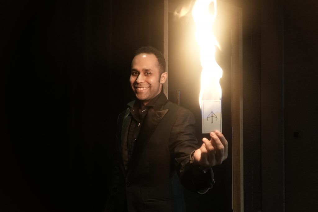 magician with playing card on fire in his hand