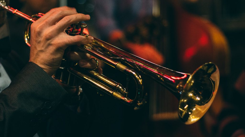 hands playing a trumpet in darkened lighting