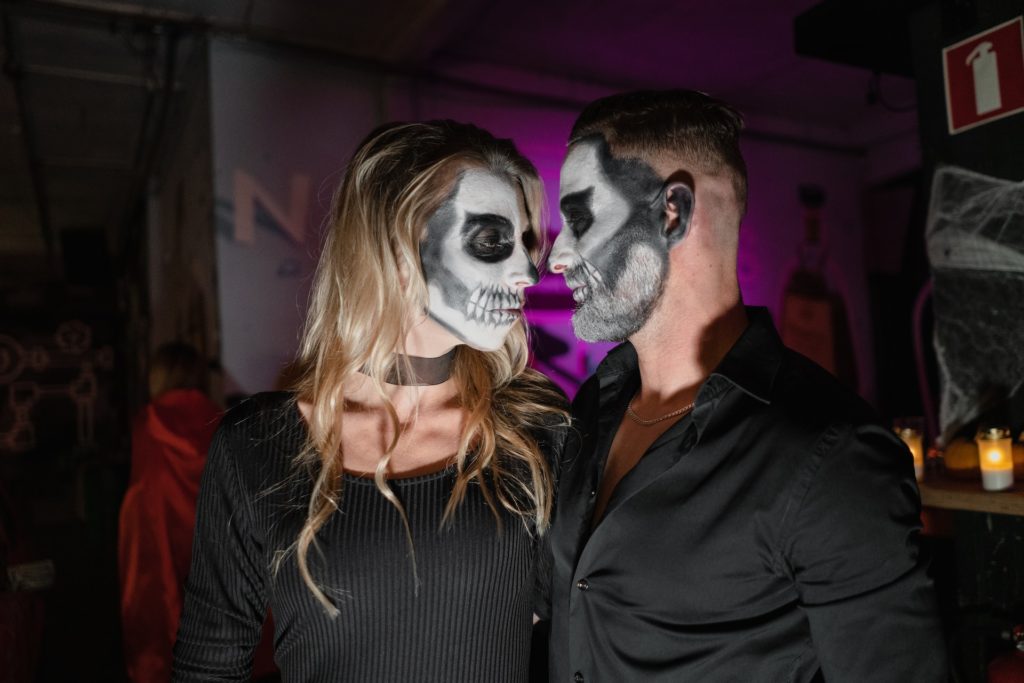 costumed man and woman with skull face painting looking at each other