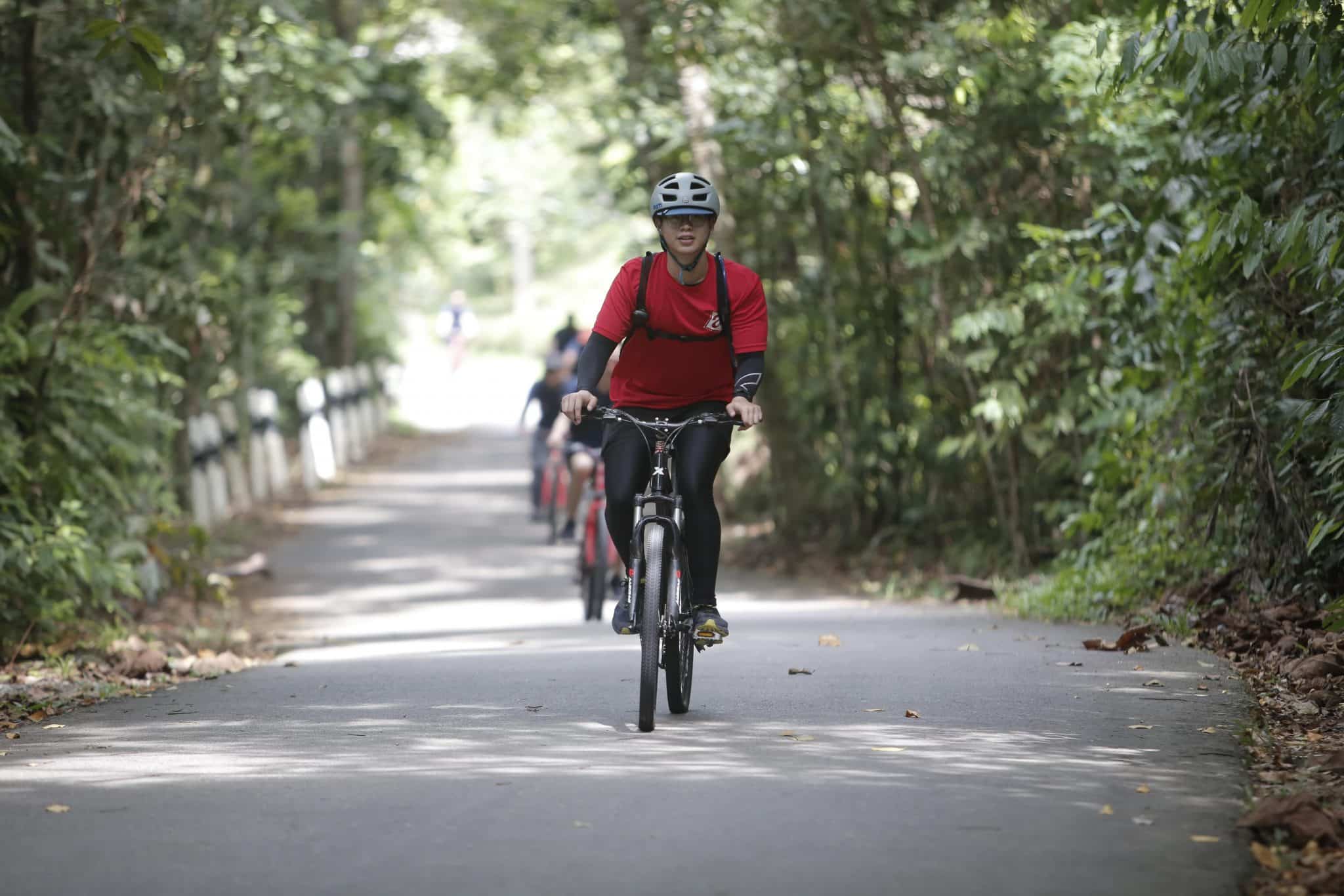 bike tour guide leading group of single file cyclists around pulau ubin in singapore bike trail