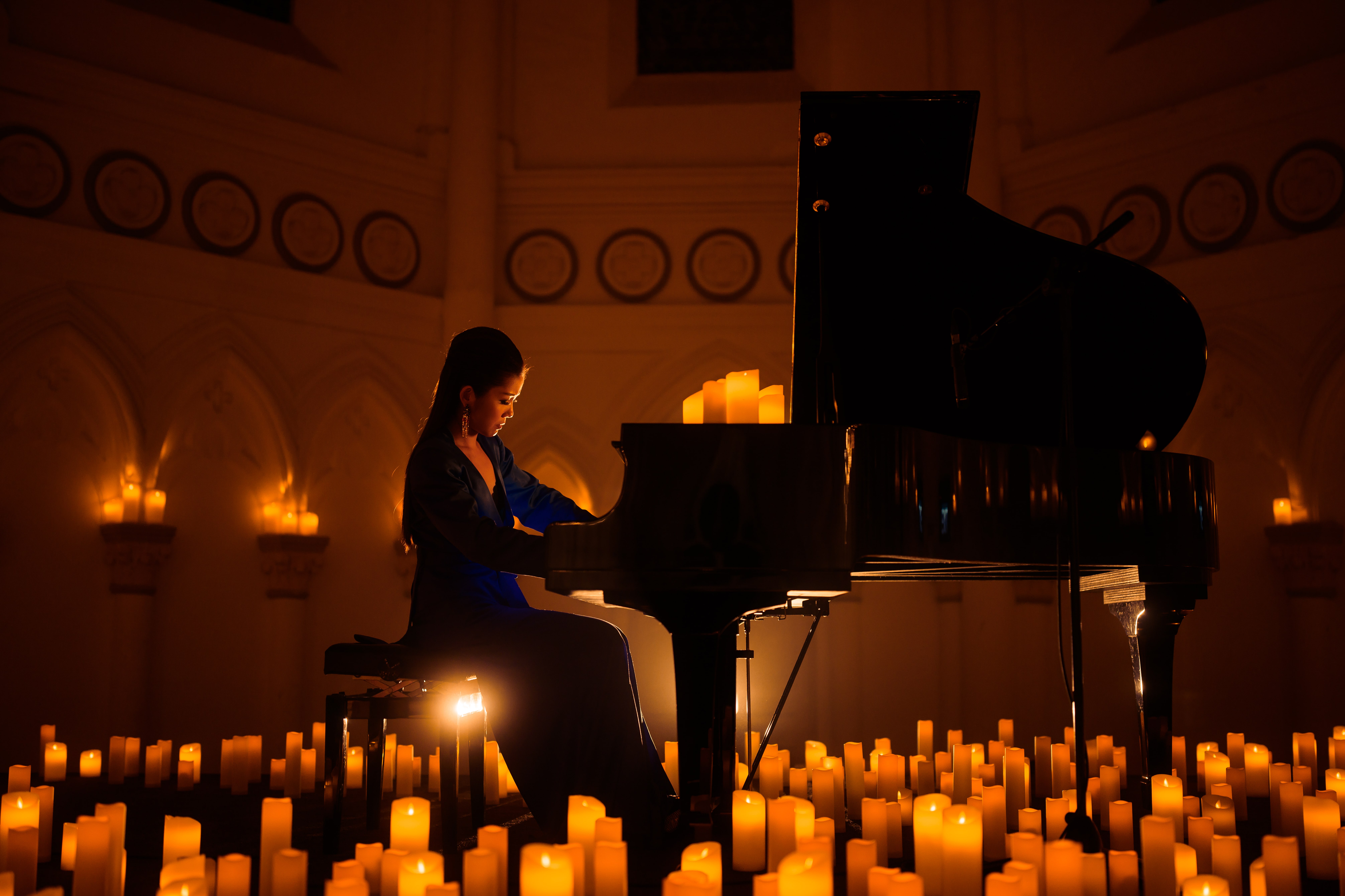 pianist performing surrounded by candles, as seen from the side