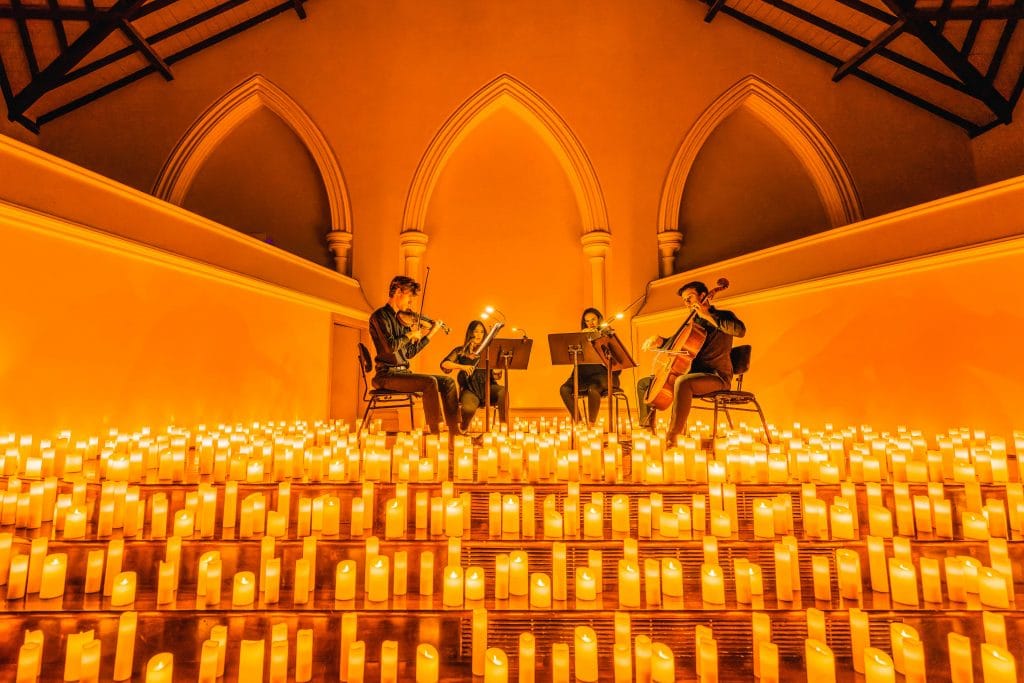 string quartet performing on makeshit stage surrounded by candles